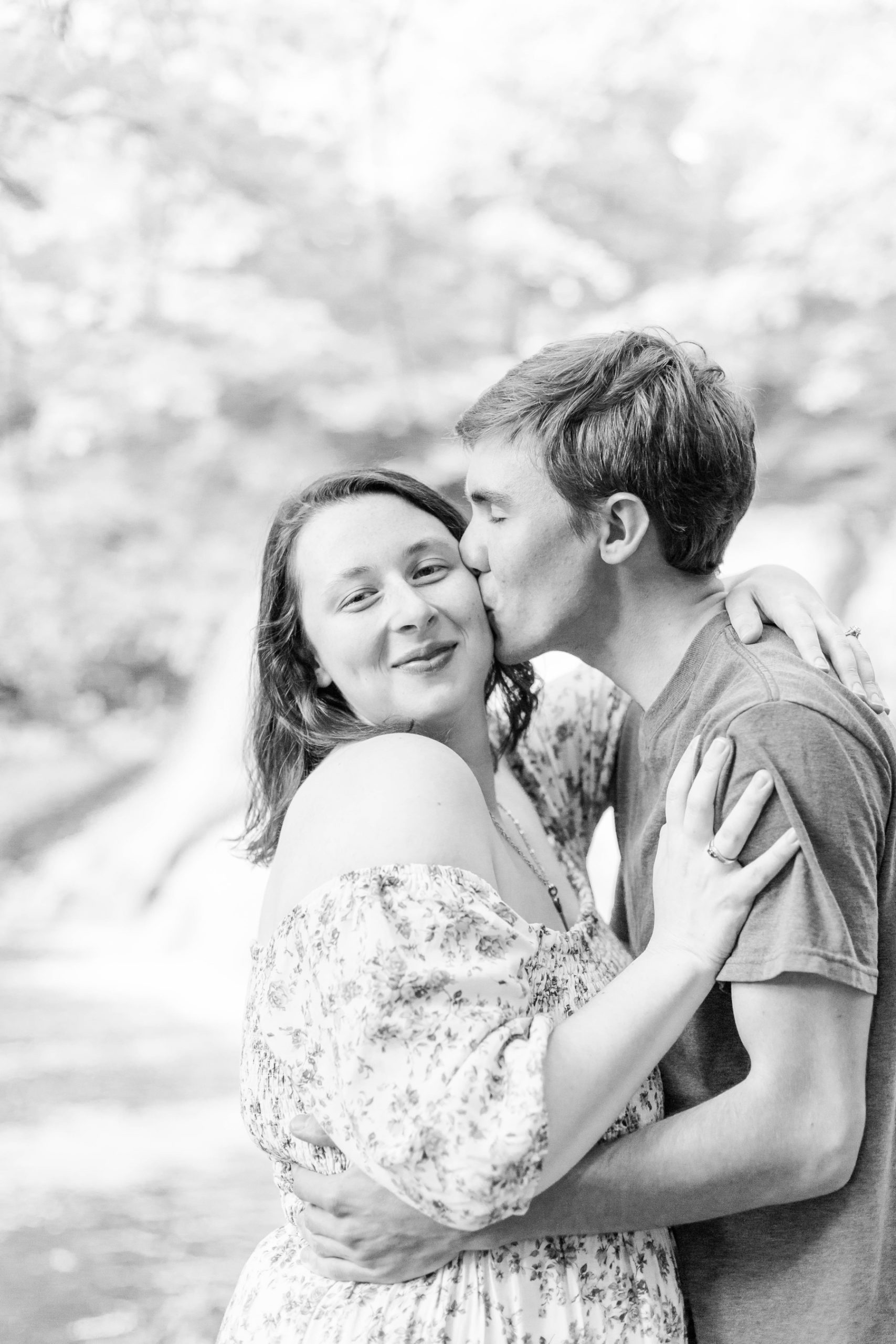 Guy kisses his fiancé on the cheek while she smiles at the camera at Wadsworth Fall Engagement Session