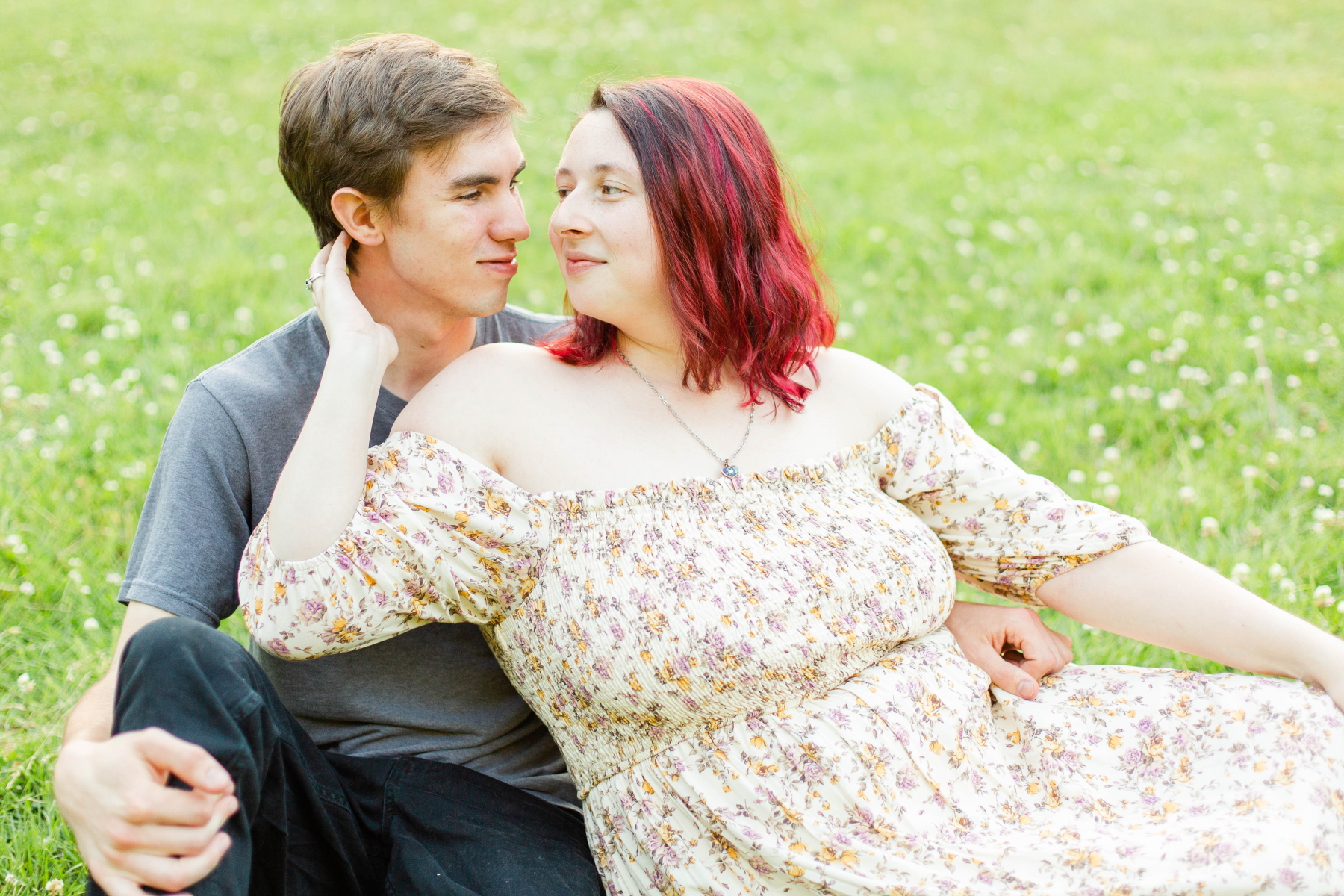 Couple sits in the grass and stare lovingly at each other at Wadsworth Fall Engagement Session