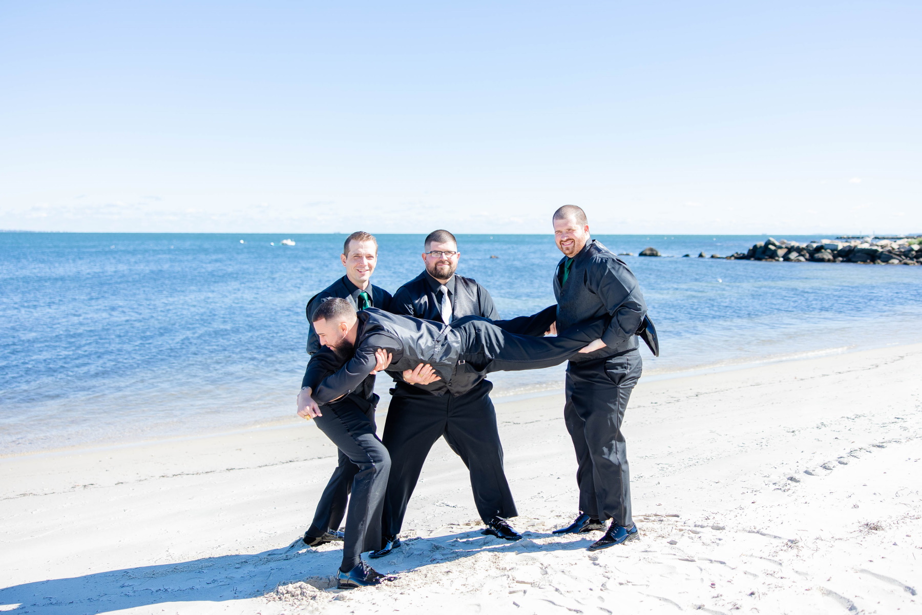 Groomsmen and groom hold best man in the air at Great Neck Country Club Wedding
