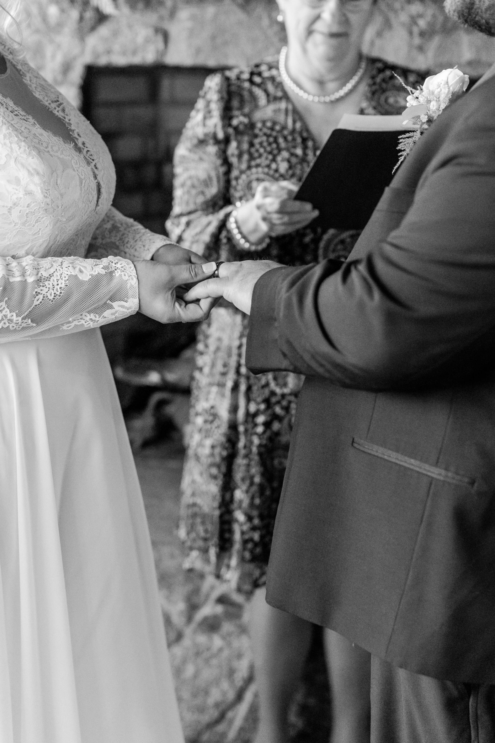 Close up photo of bride placing the wedding band on groom's finger during ceremony at Great Neck Country Club Wedding