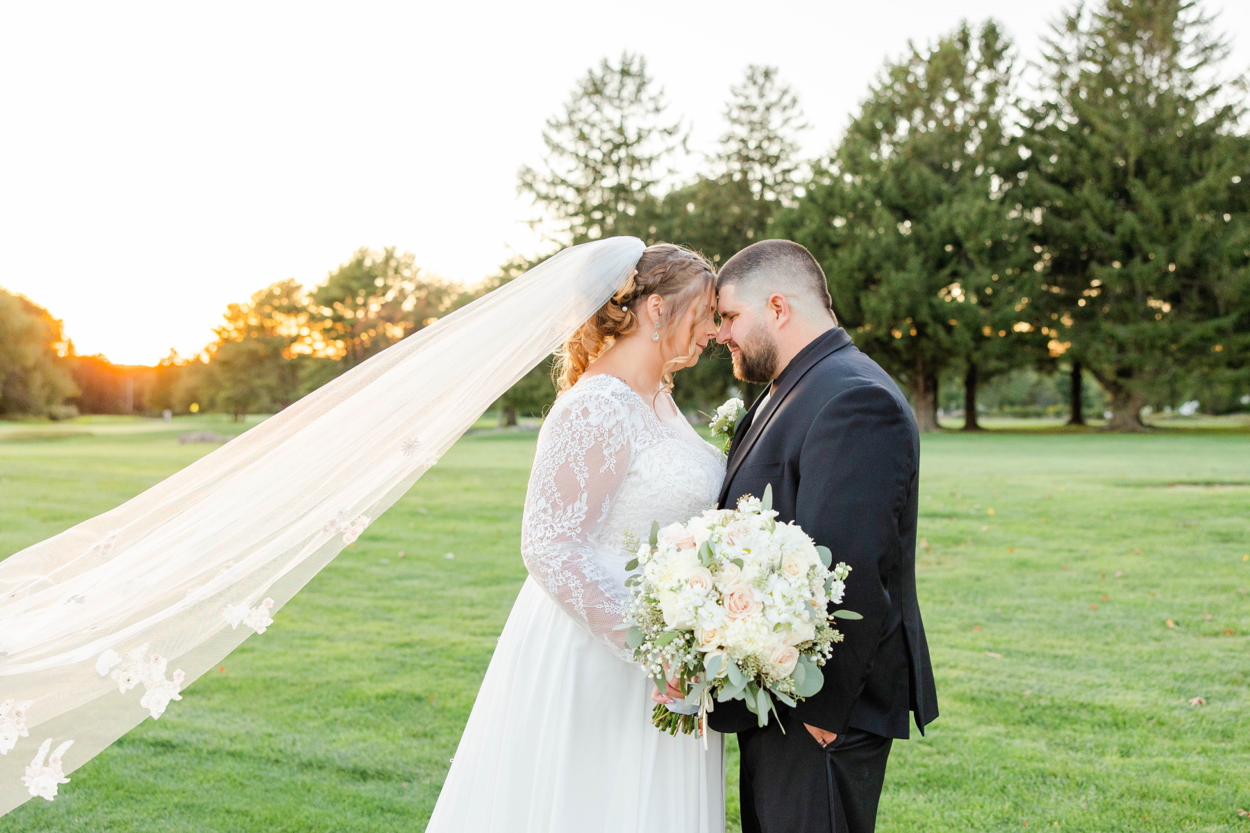 Bride and groom lean foreheads together with sunset in the background at Great Neck Country Club Wedding