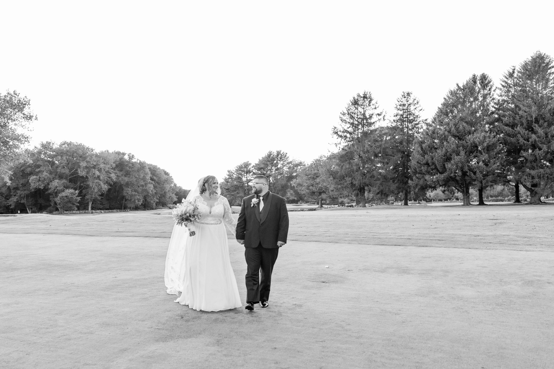 Bride and groom walk towards camera while holding hands at Great Neck Country Club Wedding